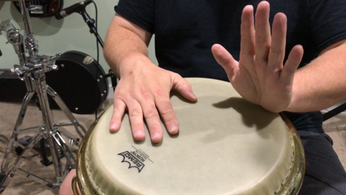 wrist is resting on the drum with fingers pointing straight up in preparation for toe stroke on the conga head